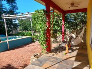 eine Terrasse mit einer Hängematte und einem Pool in der Unterkunft Casita Amarilla in the Yellow City in Izamal