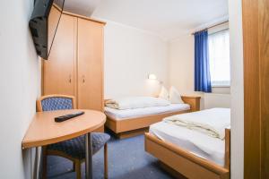 een kamer met twee bedden, een tafel en een bureau bij Landhaus Gretl by S4Y in Krumpendorf am Wörthersee