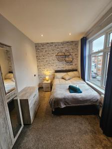 a bedroom with a large bed and a brick wall at Tudor Road House in Leicester