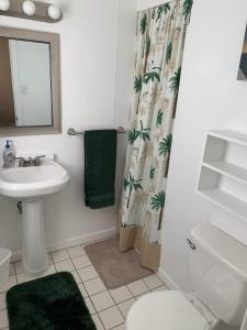 a bathroom with a sink and a toilet and a shower curtain at Sebastian Gardens Inn & Suites in Sebastian