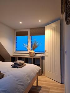 een slaapkamer met een bed en een groot raam bij Bundi Beach in Egmond aan Zee