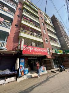 un hombre está parado frente a un edificio en Mohammadia Restaurant & Guest House Near United Hospital, en Dhaka