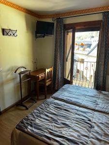 a bedroom with a bed and a desk and a window at CASA PELENTOS Sandinies in Sandiniés