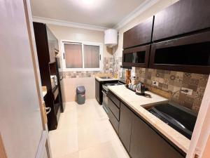 eine kleine Küche mit schwarzen Schränken und einem Waschbecken in der Unterkunft stylish with garden 3bdrm 2 bath in Madinaty
