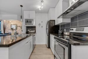 een keuken met witte kasten en roestvrijstalen apparatuur bij Gastown Downtown Apartment very central in Vancouver
