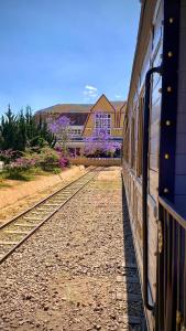 Ein Zug befindet sich auf den Gleisen neben einem Gebäude. in der Unterkunft Tường Vy Dalat Central in Da Lat