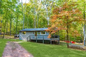 a small blue house in the middle of a forest at Cabin w Hot Tub, Huge Deck, Firepit & WiFi! in Hedgesville