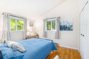 a bedroom with a blue bed and two windows at Cabin w Hot Tub, Huge Deck, Firepit & WiFi! in Hedgesville