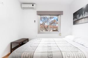 a white bedroom with a large bed and a window at La Sagrera House in Barcelona