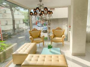 加提歐馬里的住宿－Le Cinema Gatteo Mare，客厅配有两把椅子、一张沙发和一个吊灯。