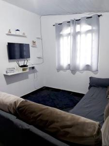 a bedroom with a bed and a window and a television at Casa inteira em chácara, 20 min centro. in Curitiba