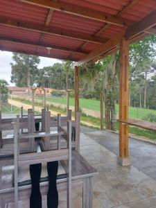 a wooden bench under a pavilion on a patio at Casa inteira em chácara, 20 min centro. in Curitiba