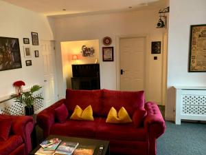 a living room with a red couch with yellow pillows at The Wizard's Loft in Alnwick