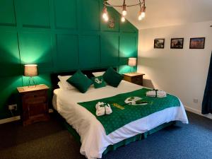 a green bedroom with a bed with towels on it at The Wizard's Loft in Alnwick