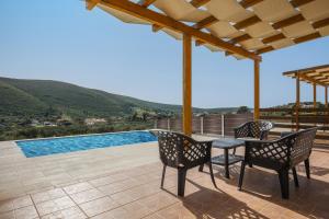 a patio with a table and chairs and a swimming pool at Maritina Houses in Anafonítria