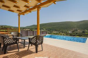 a patio with a table and chairs and a swimming pool at Maritina Houses in Anafonítria