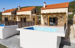 a villa with a swimming pool in front of a house at Maritina Houses in Anafonítria