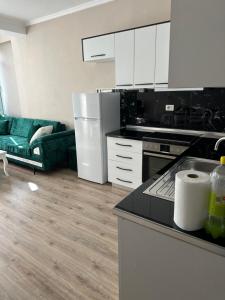 a kitchen with white cabinets and a green couch at Luxury apartment in the calmest area in Tirana