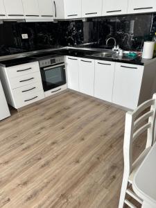 a kitchen with white cabinets and a wooden floor at Luxury apartment in the calmest area in Tirana