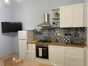 a kitchen with white cabinets and a stove and a refrigerator at A due passi dal mare in Castiglioncello