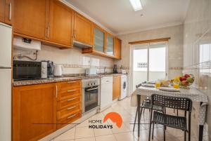 a kitchen with wooden cabinets and a table with chairs at #001 Cosy flat in Old Town near beach in Albufeira