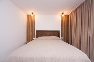 DENTA SUPORT HOTEL في رمينكو فيلتشا: غرفة نوم بسرير كبير مع شراشف بيضاء