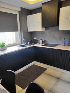 a kitchen with white cabinets and a sink and a window at Apartamenty Rzucewska 87 in Żelistrzewo