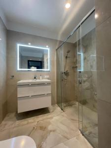 uma casa de banho com um chuveiro, um lavatório e um espelho. em Copernicus Sky Apartment em Zielona Góra
