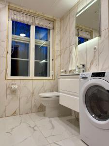 a bathroom with a washing machine and a toilet at Veski Apartment in Kuressaare