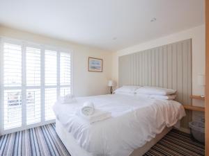 a bedroom with a large white bed with towels on it at Beachside in Polzeath