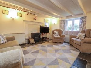 a living room with couches and a tv and a fireplace at 2 Rose Cottages in Looe