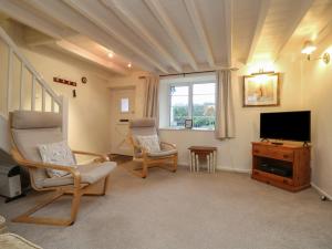 a living room with two chairs and a flat screen tv at 3 Rose Cottages in Looe