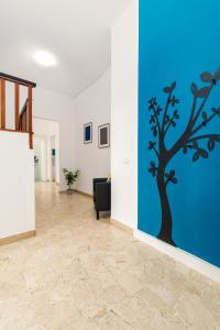 einen Flur mit einer blauen Wand mit einem Baumbild in der Unterkunft Blue Apartment in Cesano Boscone
