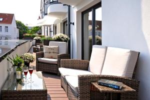un patio con sedie in vimini e un tavolo sul balcone. di Passepartout a Norderney