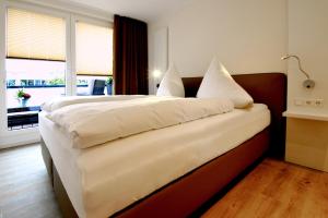 una camera da letto con un letto grande con lenzuola e cuscini bianchi di Passepartout a Norderney