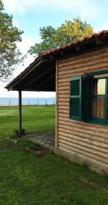 a small house with a green window and a field at Wooden beach house / Nea Roda, Halkidiki in Nea Roda