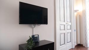 TV de pantalla plana colgada en una pared blanca en Casa Latilla, en Nápoles