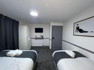 a hotel room with two beds and a television at OYO Greenway Stays in Uxbridge