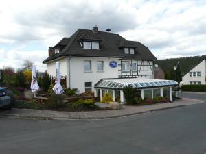 a large white house with a porch in front of it at Hotel Am Salzberg in Philippsthal