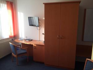 a room with a desk and a cabinet with a television on it at Hotel Am Salzberg in Philippsthal