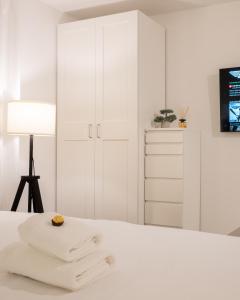 a white bedroom with white cabinets and towels on a bed at Goldberg Apartments Osijek in Osijek