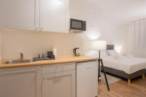 uma cozinha com um lavatório e uma cama num quarto em Goldberg Apartments Osijek em Osijek