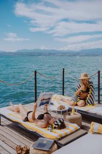 two people laying on beds on a dock on the water at AQVA Boutique Hotel (Adults Only) in Sirmione