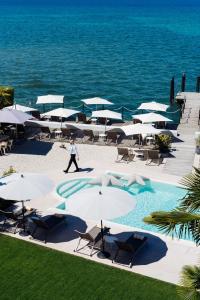 a person walking by a pool with umbrellas and the ocean at AQVA Boutique Hotel (Adults Only) in Sirmione
