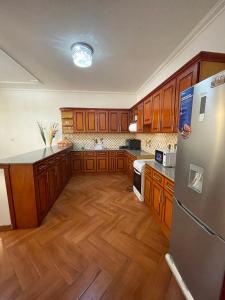 a kitchen with wooden cabinets and a stainless steel refrigerator at METRO Deluxe Specious Home in a Great Neighborhood!! in Addis Ababa