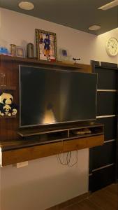 a large flat screen tv on a wooden shelf at The Harvard Home in Greater Noida