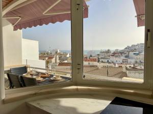 a window with a view of a city from a balcony at RosaMar apartment sea view and pool in Albufeira +27 photos