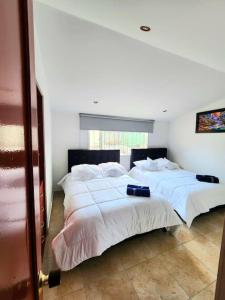2 camas en una habitación con paredes blancas en Casa Cerca del Aeropuerto: Spa con Sauna y Jacuzzi, en Bogotá