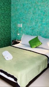 1 dormitorio con 1 cama grande y pared verde en HOTEL ALCUARA en Pereira