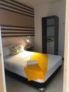 1 dormitorio con 1 cama grande con manta amarilla en HOTEL ALCUARA, en Pereira